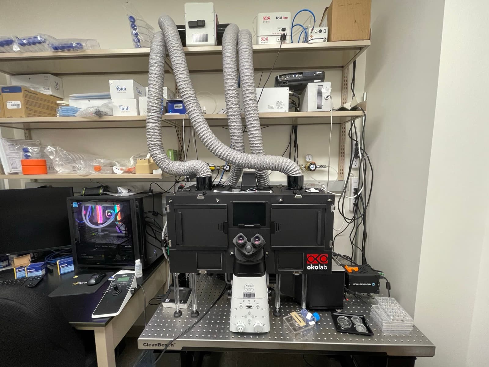Live-cell imaging rig: a research microscope inside a climate-controlled enclosure, driven by a custom-built workstation