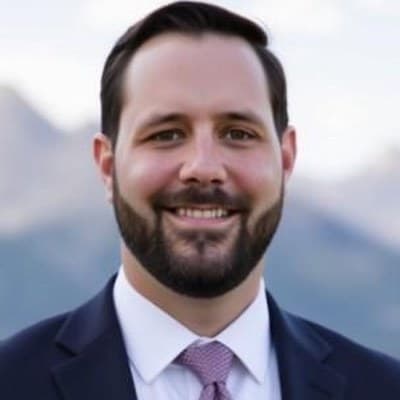 Michael Ferreyros, head and shoulders, in a suit and tie against a mountain backdrop